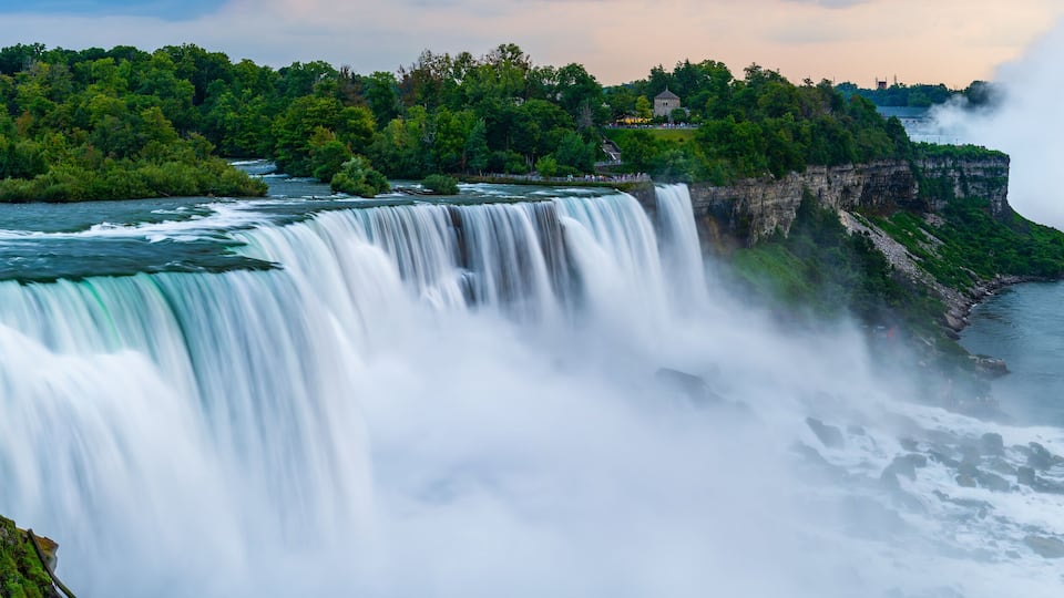 A panoramic long exposure photo of the American - Canadian waterfalls Niagara Falls in dusk.