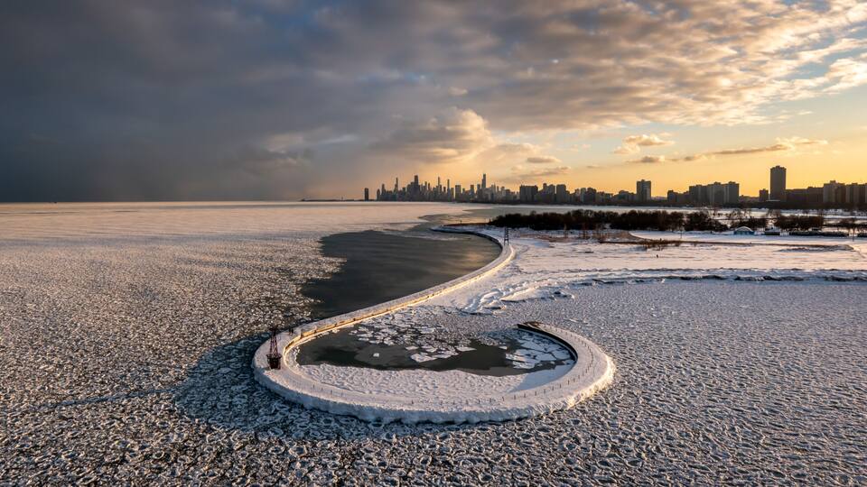 A frozen river with a city skyline in the background.