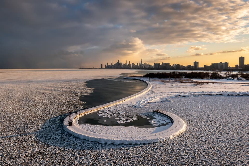 A frozen river with a city skyline in the background.