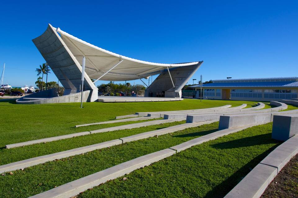 Estrutura arquitetônica moderna com um toldo branco, cercada por uma área gramada bem cuidada e caminhos de concreto.