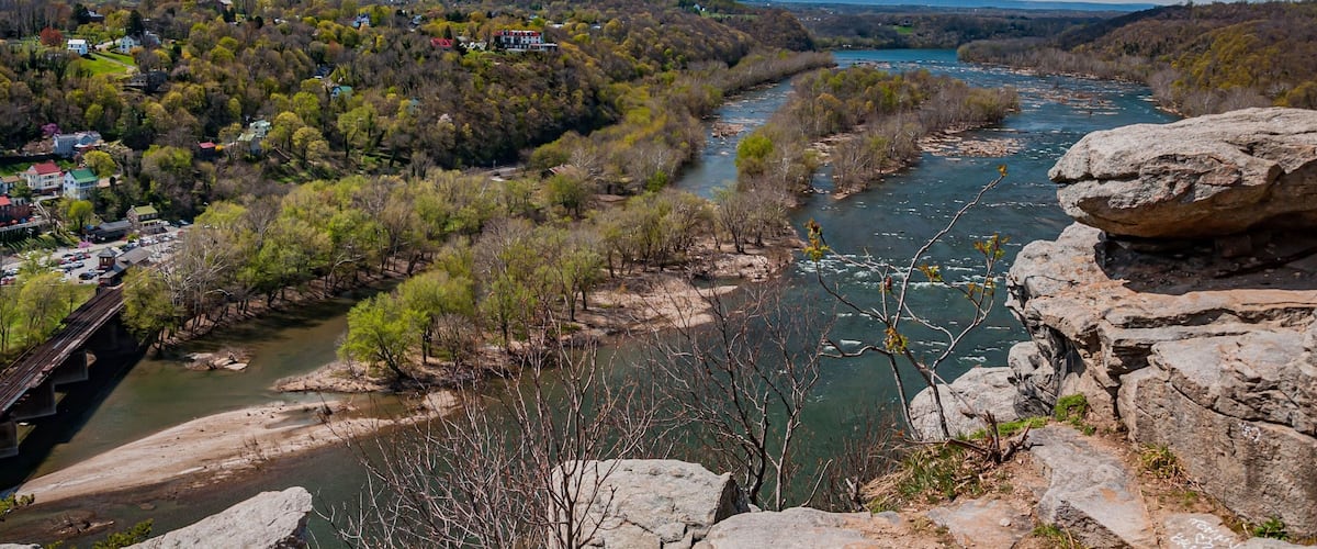 A river winding through a valley with rocky outcrops and a bridge.