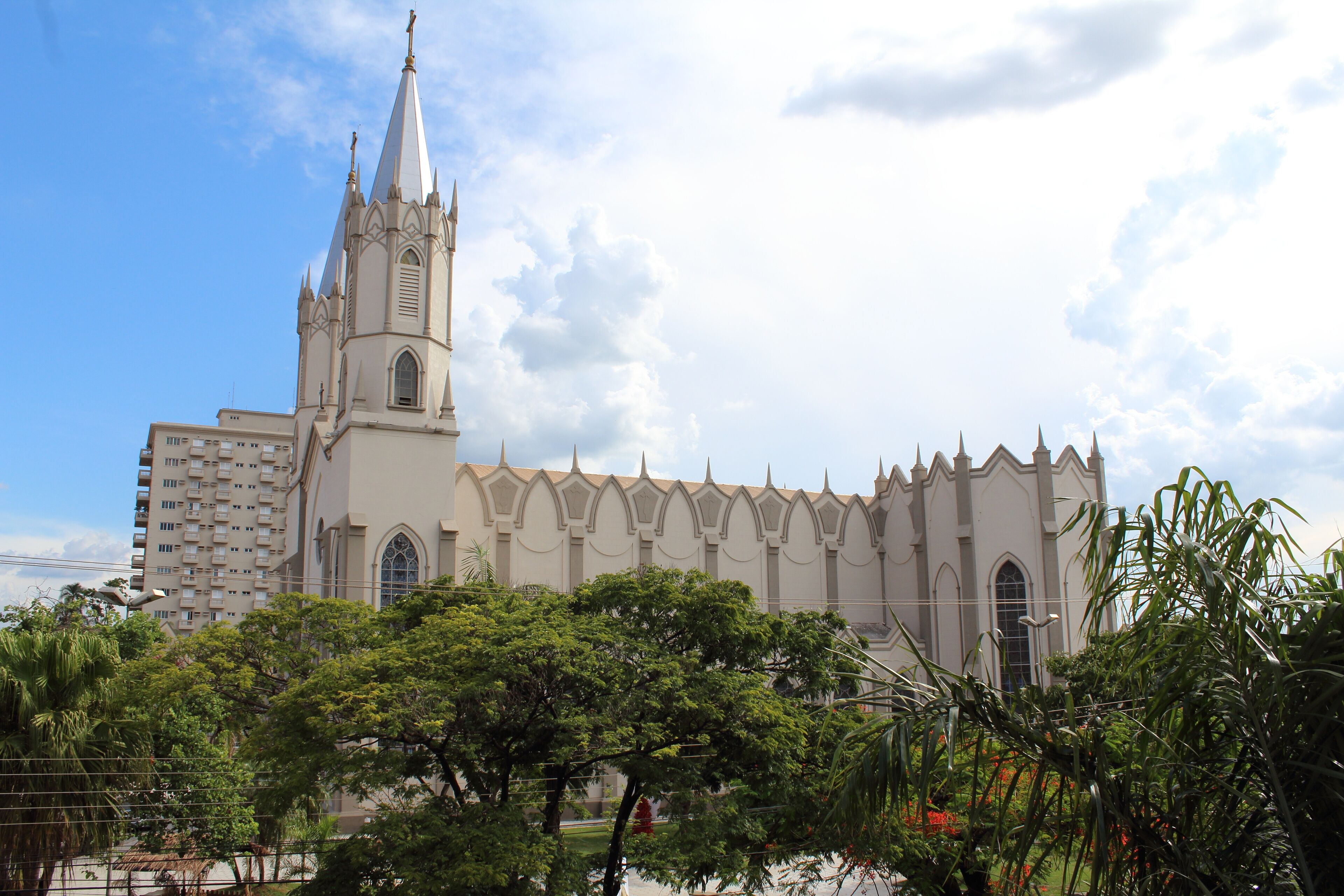 A large church with a tall spire and a modern building beside it.