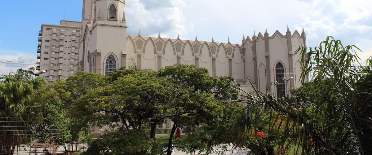 A large church with a tall spire and a modern building beside it.