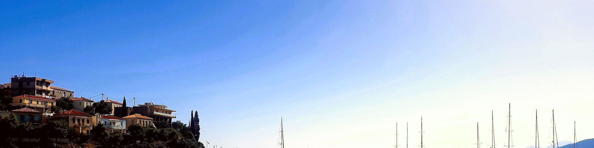 Astros a picturesque coastal town in Peloponnese, Greece, featuring its serene fishing shelter and clear azure waters. Small boats are visible floating peacefully near the shore.