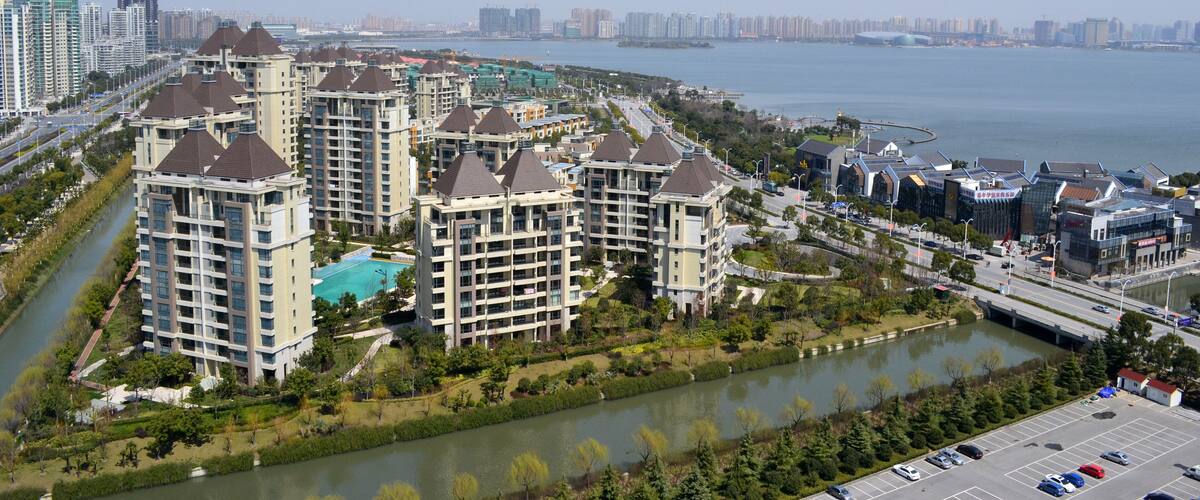 A riverside residential area with high-rise buildings, a bridge, and a distant city skyline.