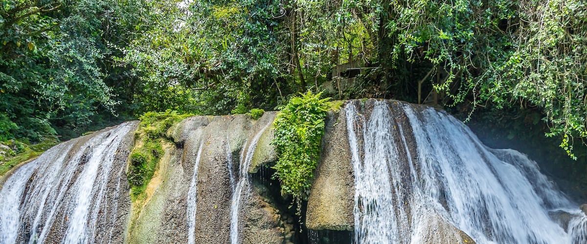 A waterfall cascading over a rock formation into a clear pool of water.