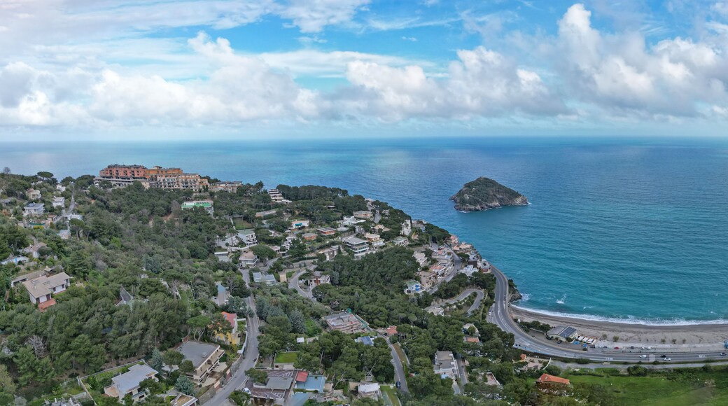 Une ville côtière avec une route sinueuse, une petite île et une mer d’un bleu limpide.