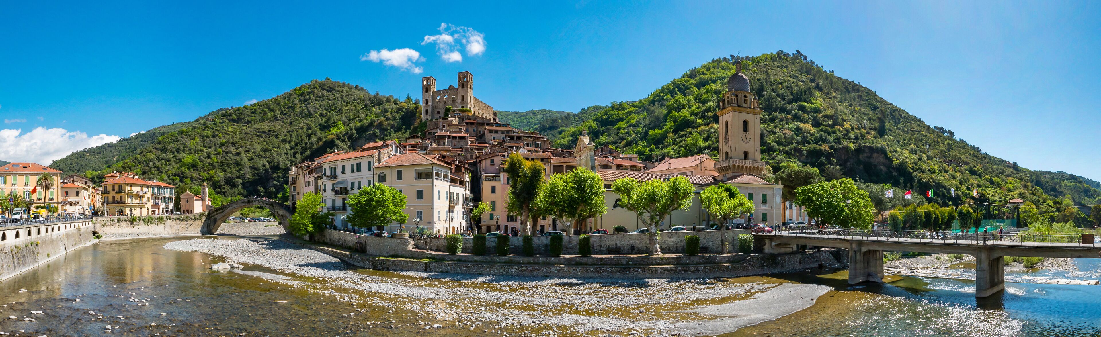 A historic town with a river, a bridge, and a hill with a church.