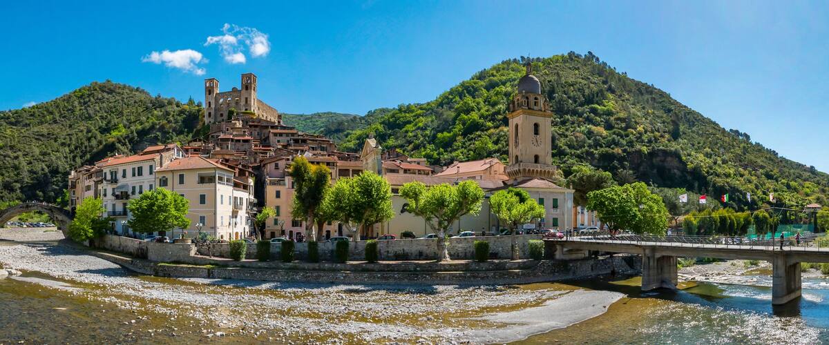 A historic town with a river, a bridge, and a hill with a church.