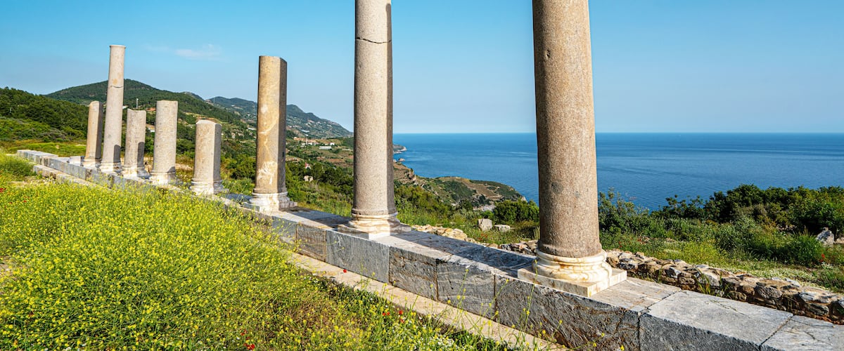 Scenic landscape of the archaeological ruins of Antiochia ad Cragum with ancient columns and stone walls perched on a high cliff overlooking the deep blue Mediterranean Sea in Gazipasa, Turkey.