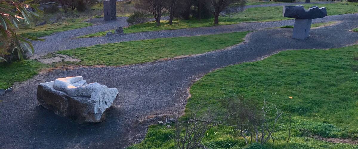 A rural landscape with a winding path, stone structures, and a sunset in the background.