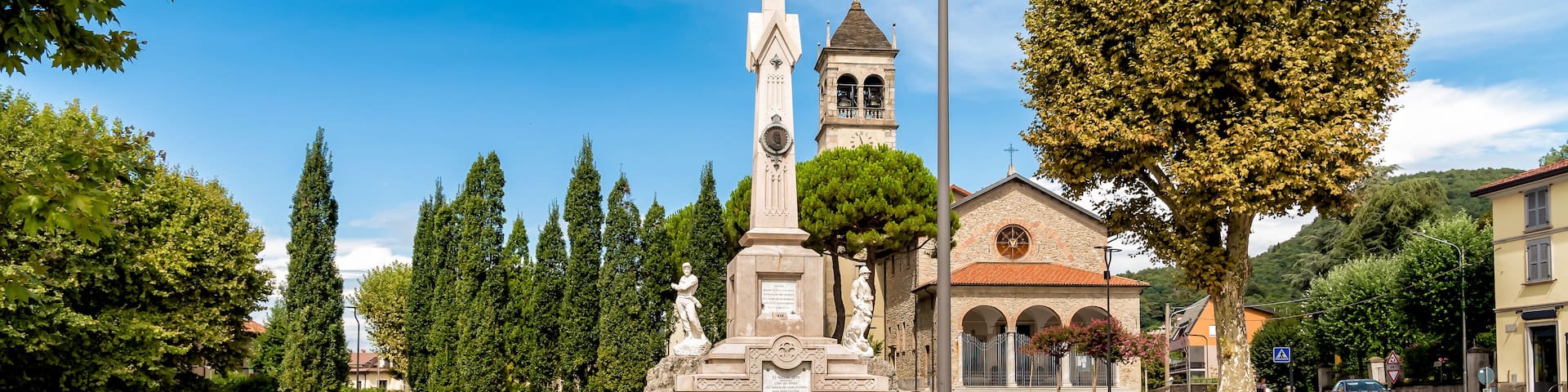 A monument with statues, a church, and a clear blue sky.
