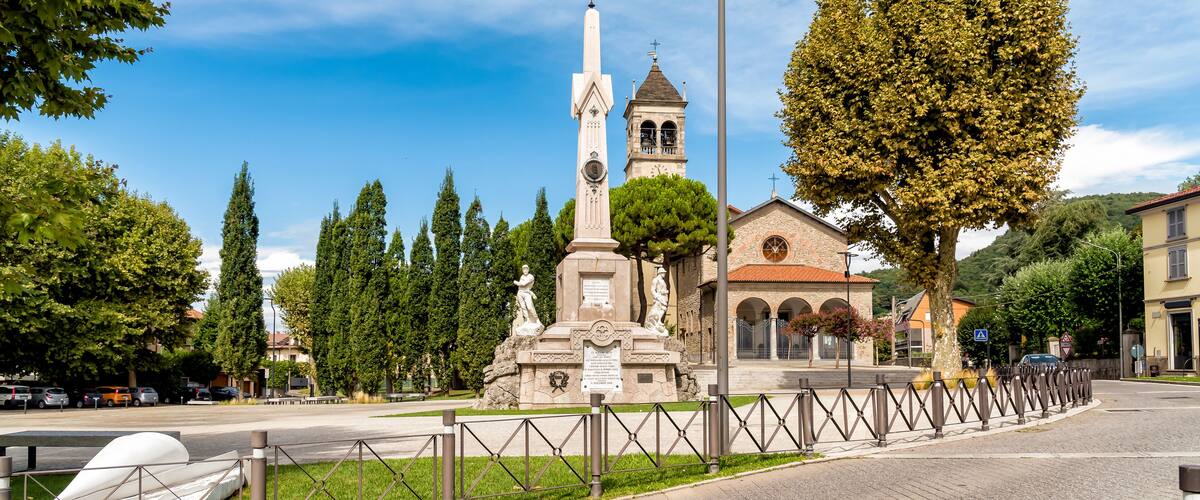 A monument with statues, a church, and a clear blue sky.
