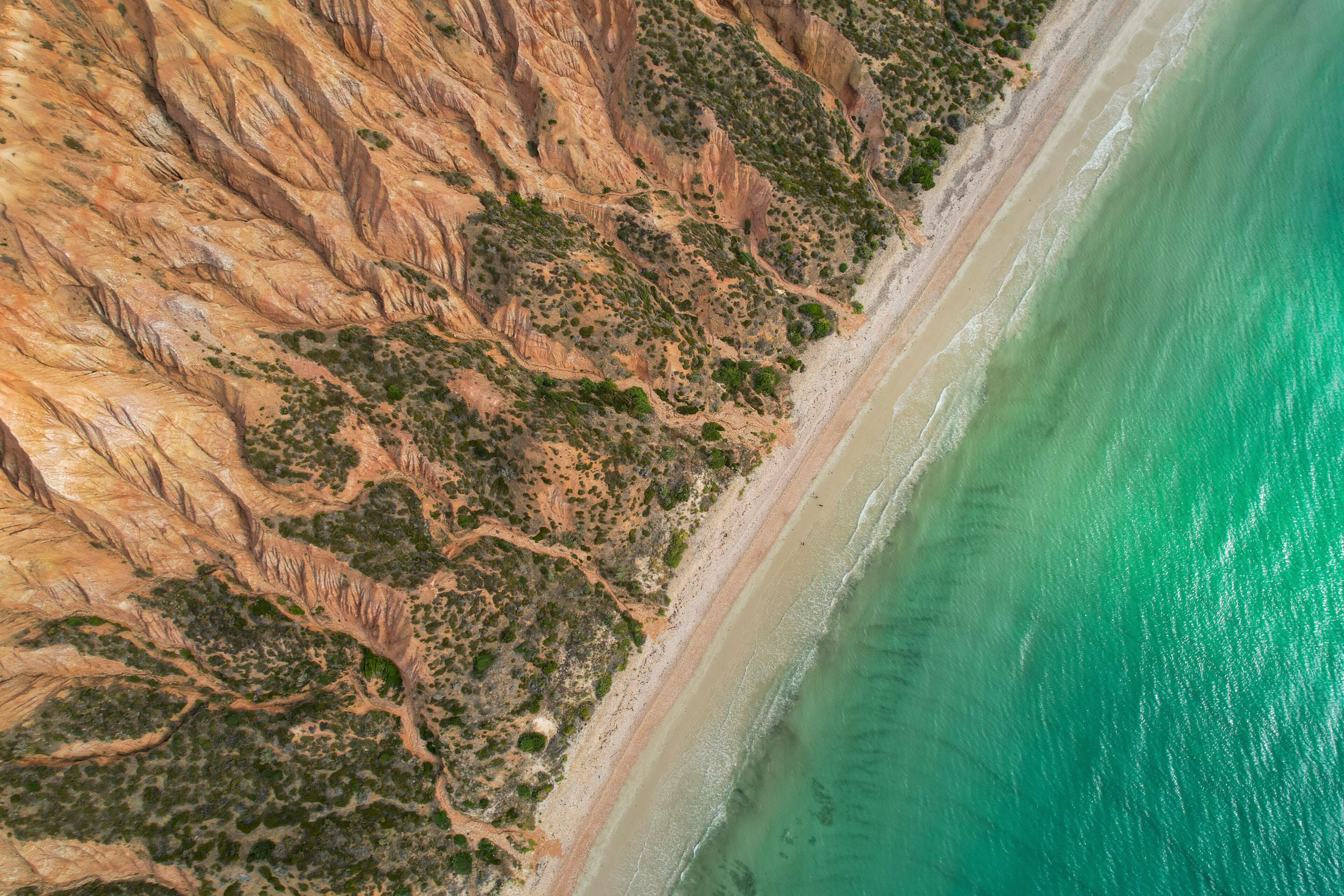 Aerial view of Sellicks Beach with turquoise clear water, sandy shore, and rocky cliffs, Fleurieu Peninsula, Australia.