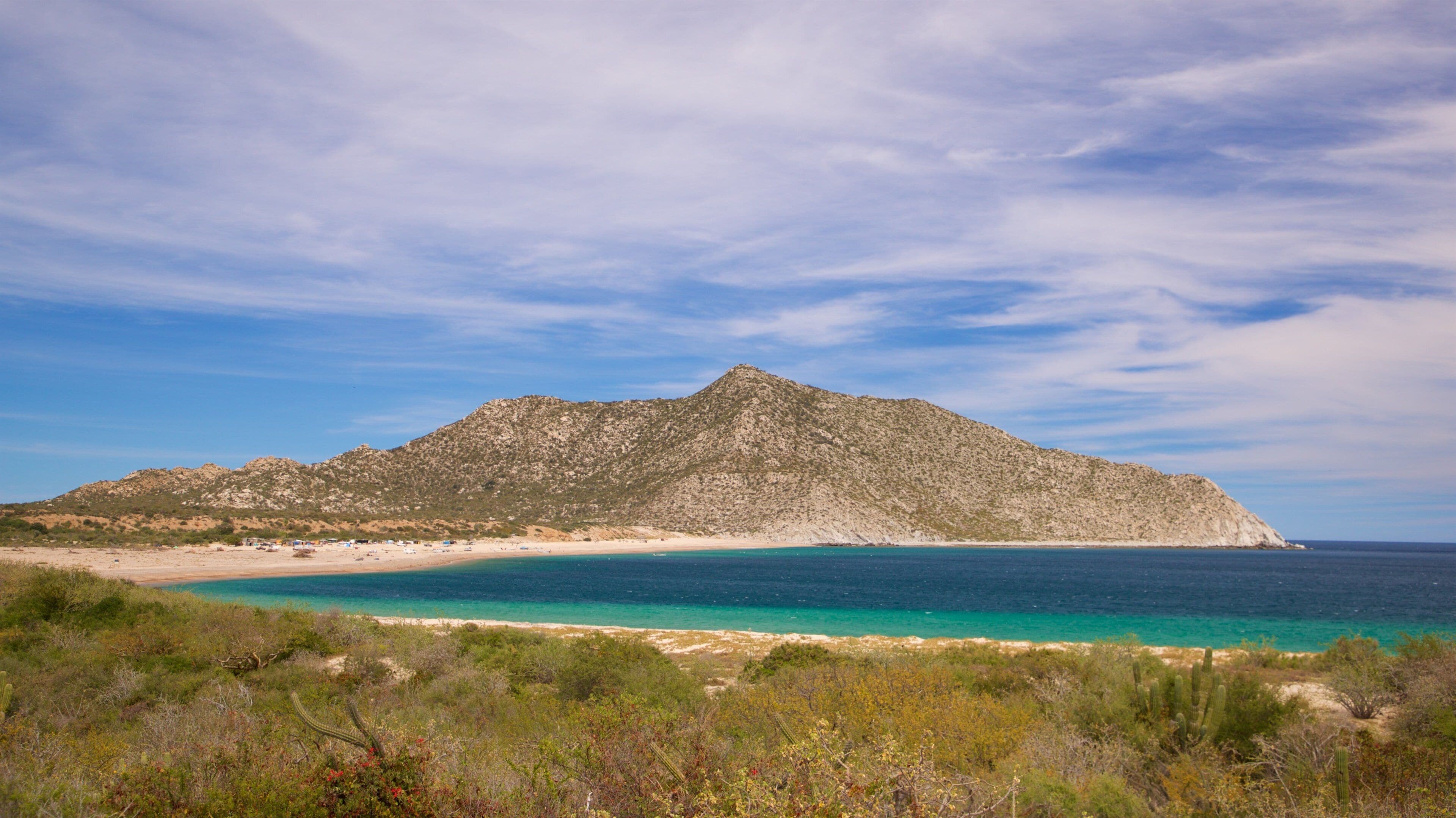 A mountainous landscape with a beach and turquoise waters.