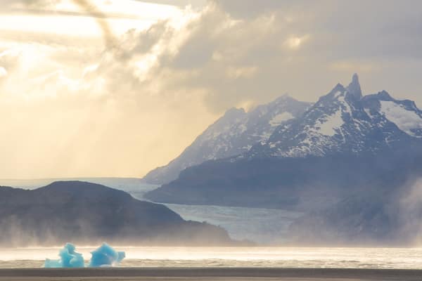 A glacier with icebergs in a mountainous landscape.