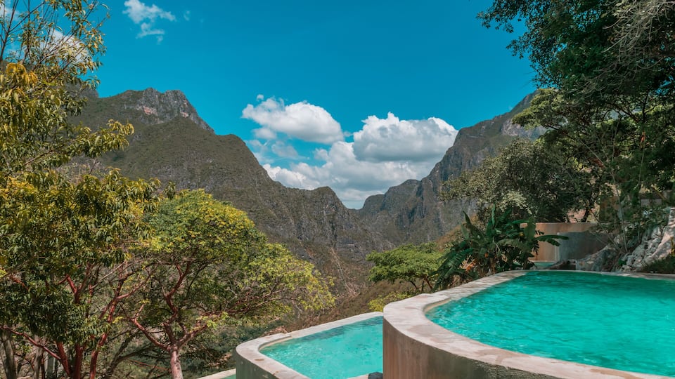 A swimming pool surrounded by lush greenery and mountains.