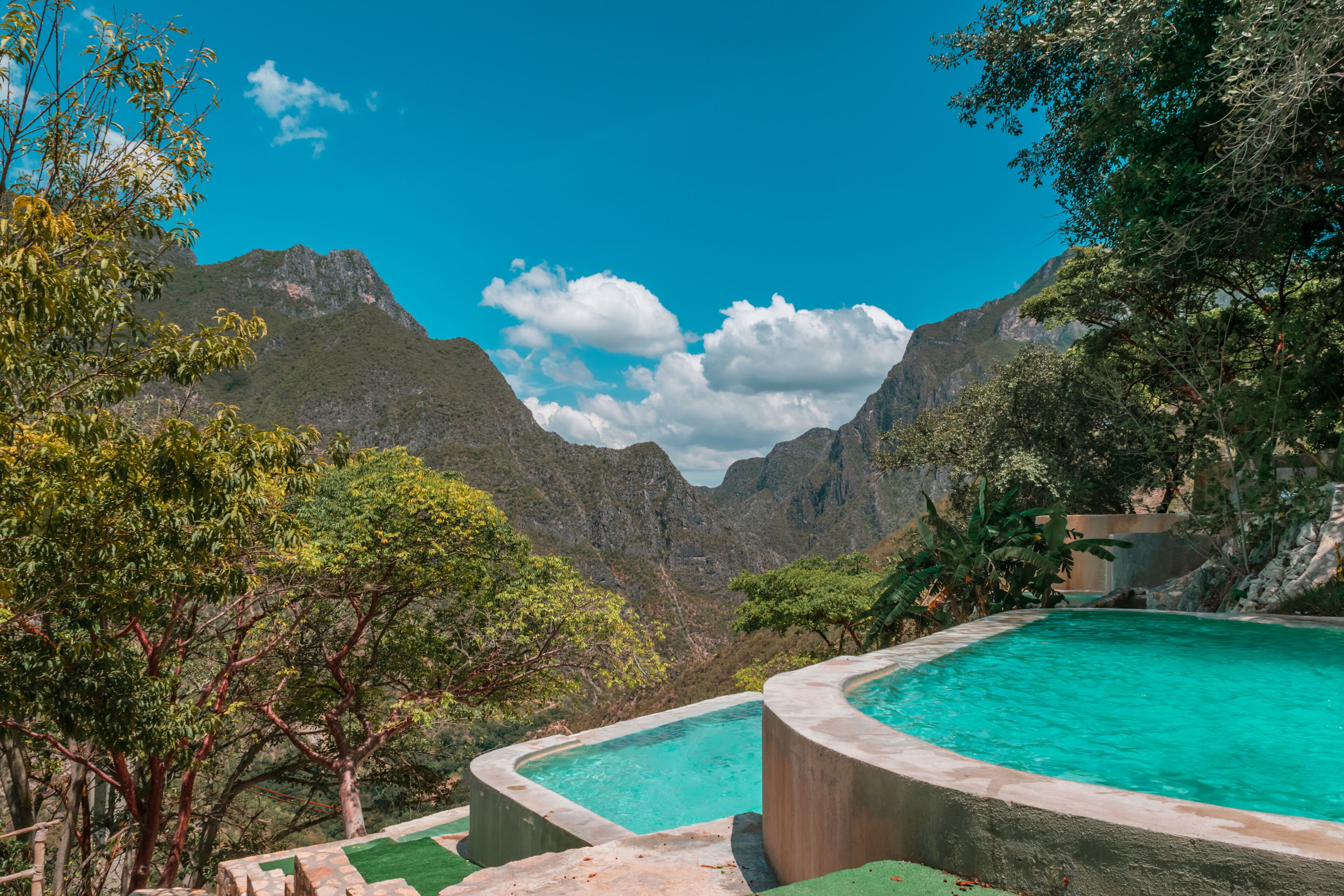 A swimming pool surrounded by lush greenery and mountains.