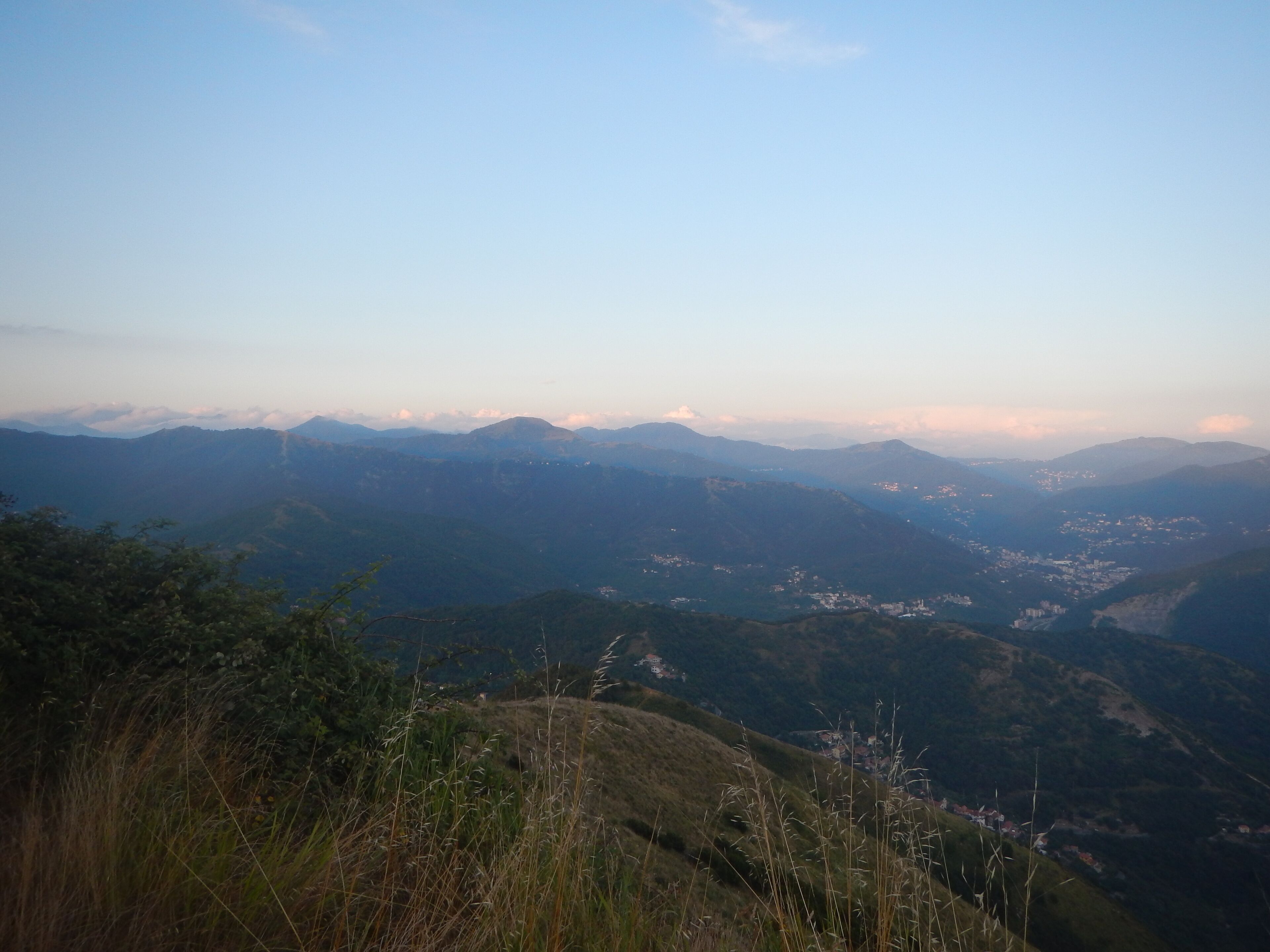 A mountainous landscape with a valley and scattered buildings.