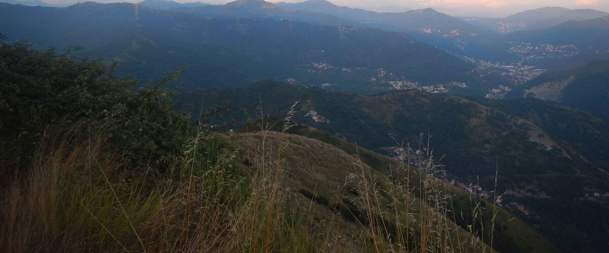 A mountainous landscape with a valley and scattered buildings.