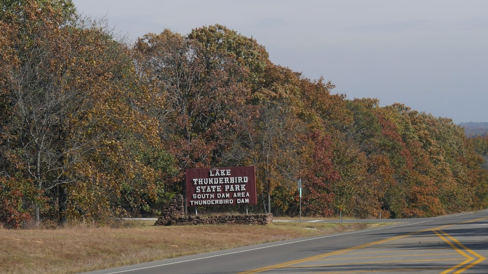 Huge billboard sign by the roadside along the Lake Thunderbird State Park in Oklahoma with fall colors in the trees in November 2017.