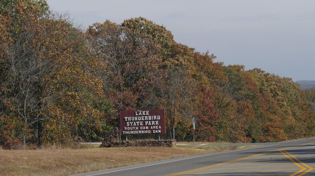 Huge billboard sign by the roadside along the Lake Thunderbird State Park in Oklahoma with fall colors in the trees in November 2017.