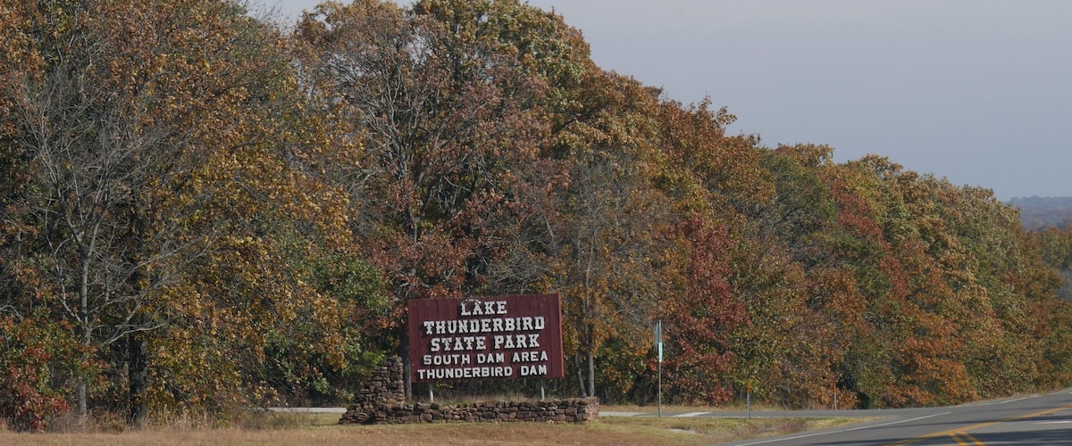 A road with a sign for Lake Thunderbird State Park South Dam Area.