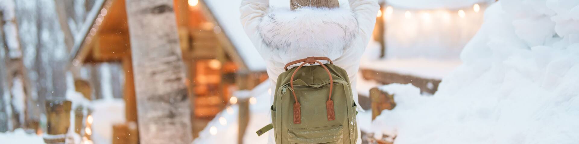 Woman tourist Visiting in Furano, Traveler in Sweater sightseeing Ningle Terrace Cottages with Snow in winter. landmark and popular for attractions in Hokkaido, Japan. Travel and Vacation concept