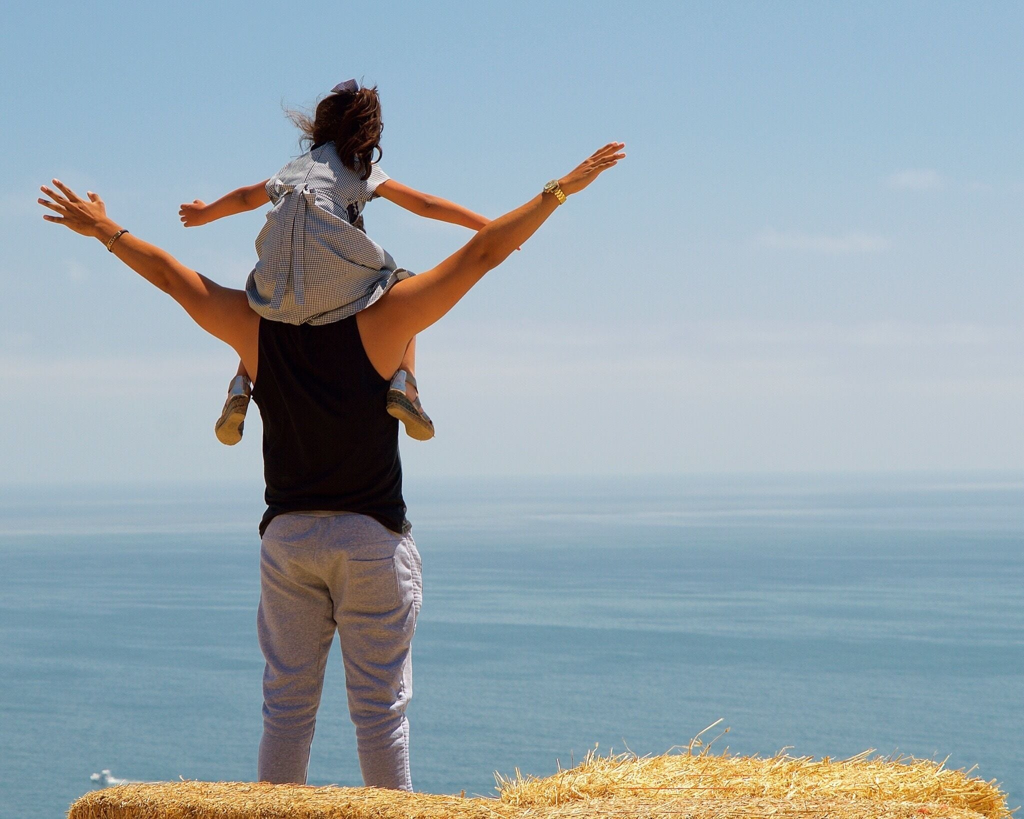 Unkown father and daughter enjoying the cool ocean breeze from the top of a cliff. 