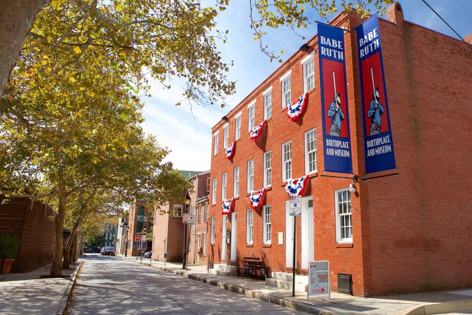 A red brick building with flags and banners, a sidewalk, and trees.