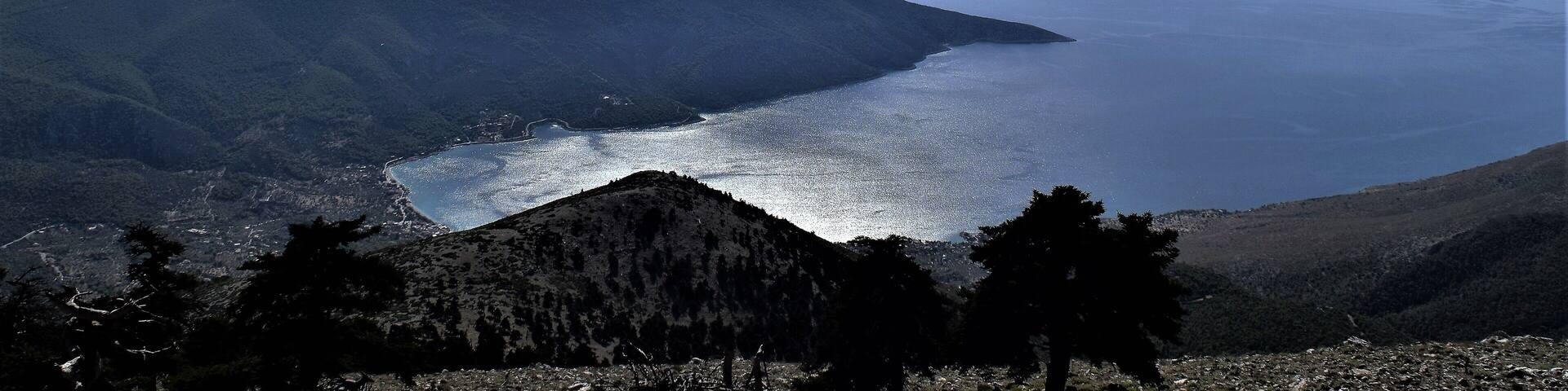 A coastal landscape with mountains, a bay, and a clear sky.