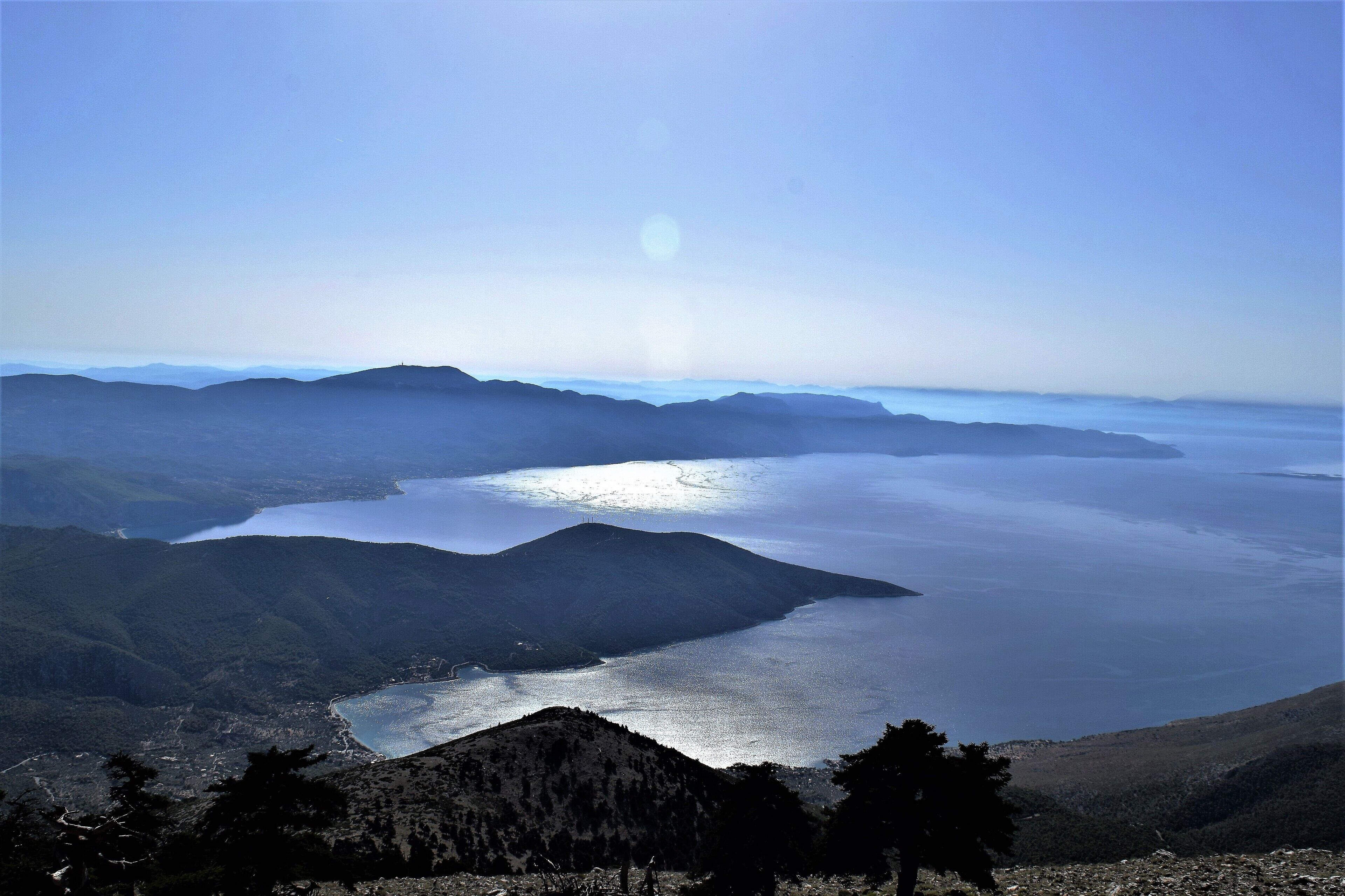 A coastal landscape with mountains, a bay, and a clear sky.