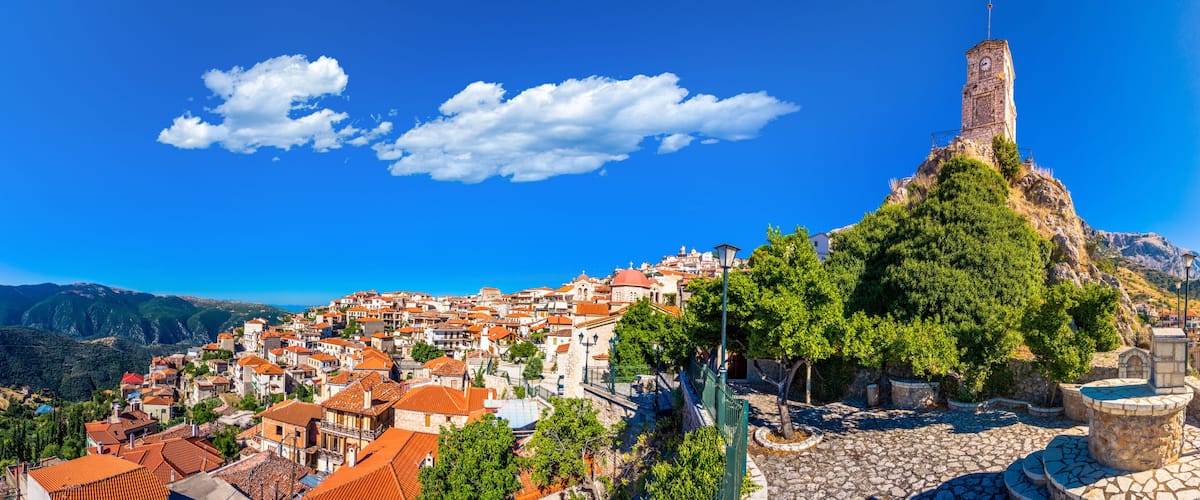 A coastal town with a prominent church tower, terraced houses, and a mountainous backdrop.