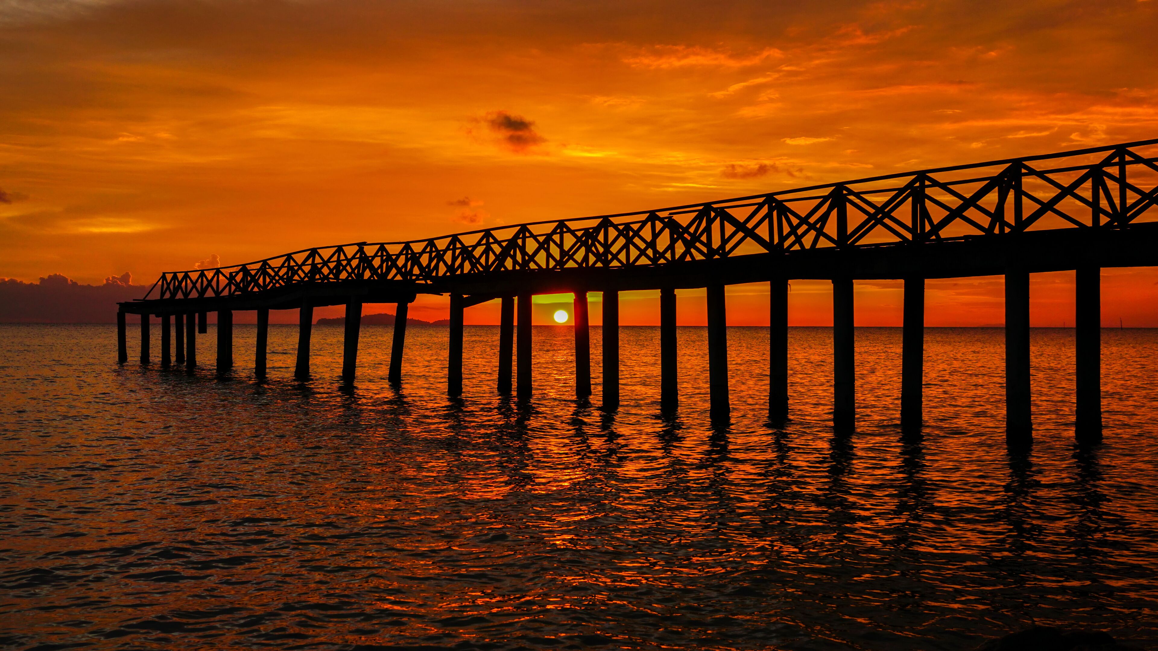 A pier extending into the water at sunset.