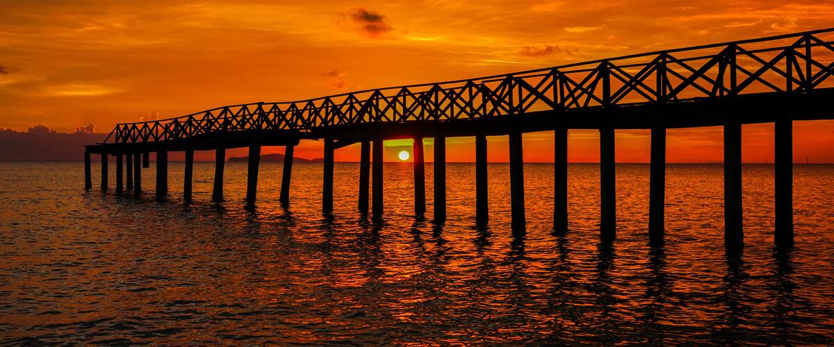 A pier extending into the water at sunset.