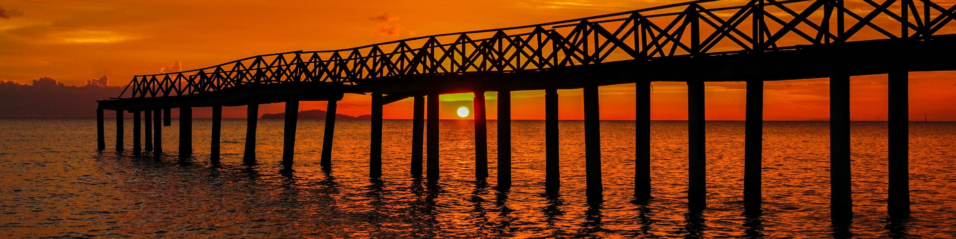 A pier extending into the water at sunset.