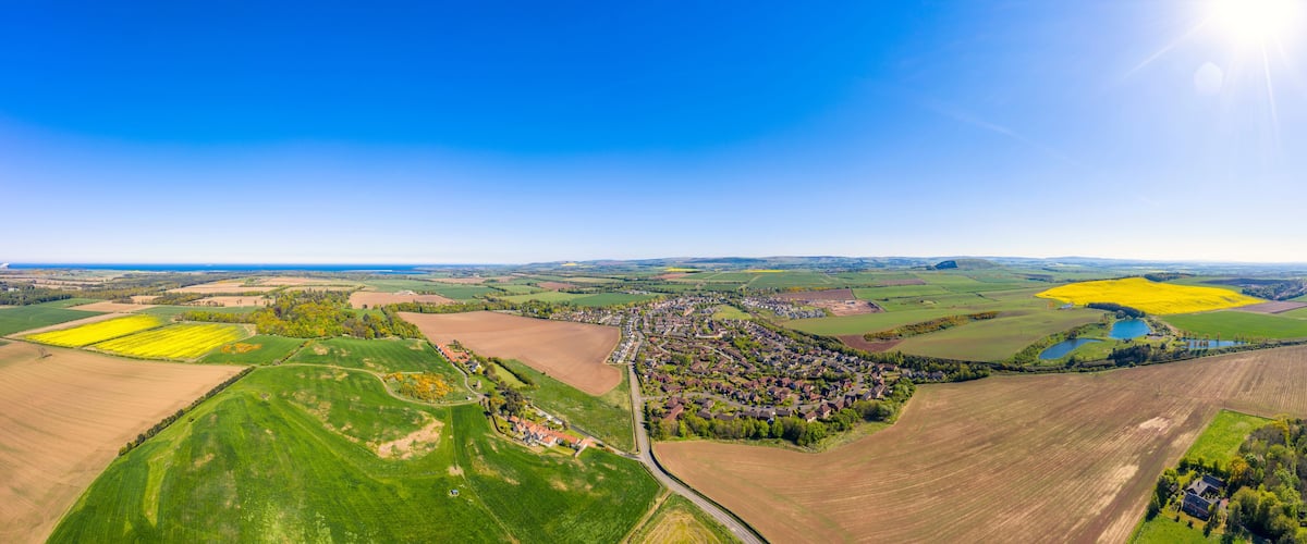 A rural landscape with fields, a village, and a lake.