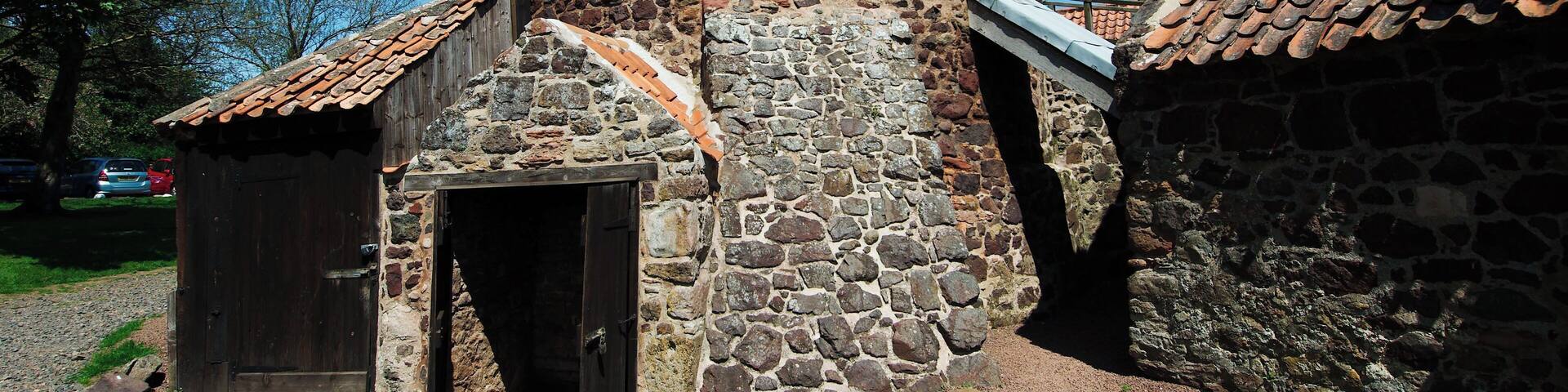 A stone building with a conical roof and a wooden door.