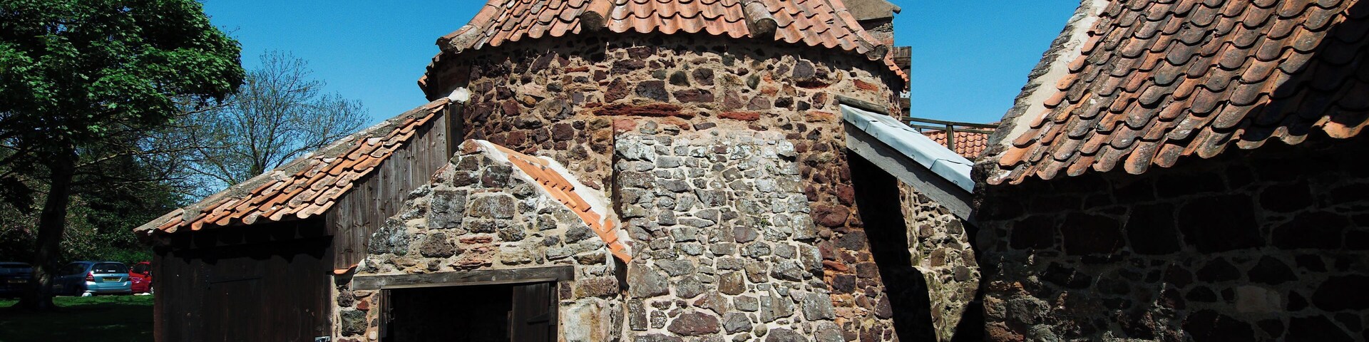 Un edificio de piedra con techo cónico y puerta de madera.