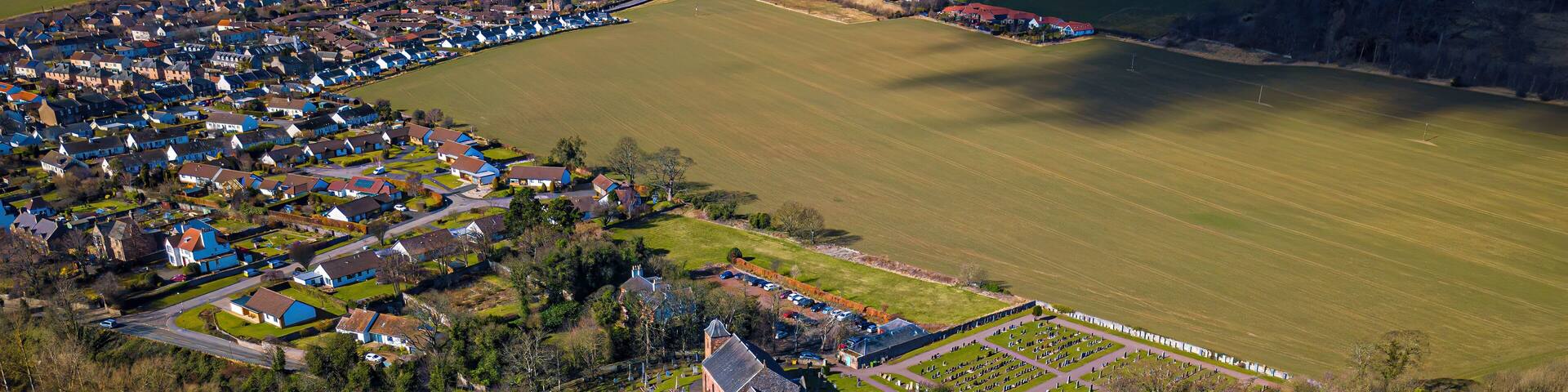 An aerial view of a village with houses, a church, and a cemetery.