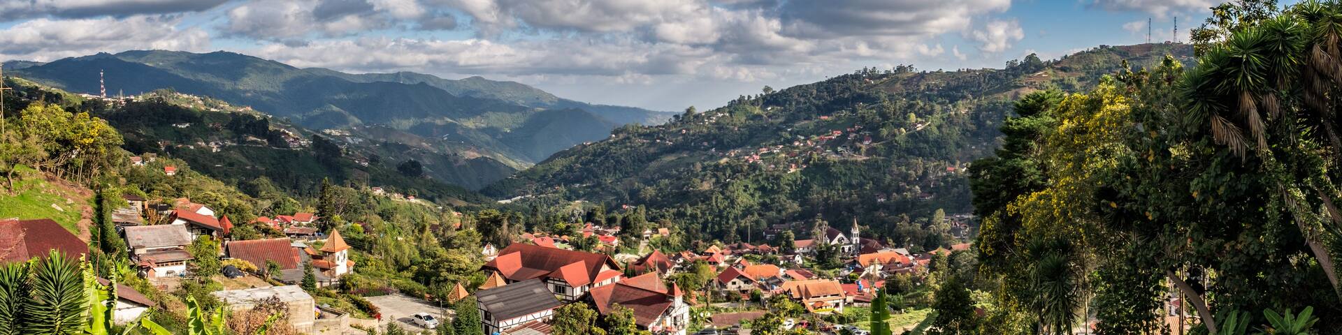 A mountainous landscape with a village, red-roofed houses, and lush greenery.