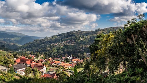 A mountainous landscape with a village, red-roofed houses, and lush greenery.