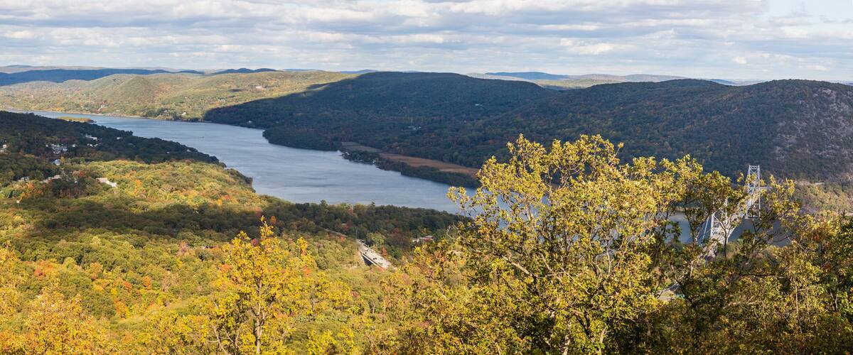 A river winding through a forested valley with hills in the background.