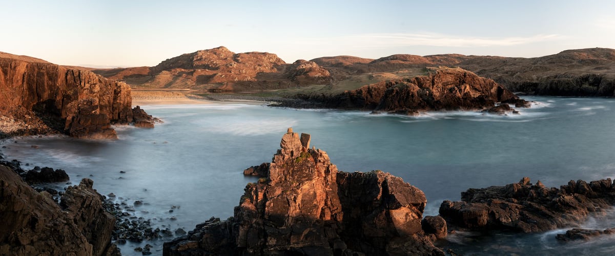 A rugged coastline with prominent cliffs and a calm sea.