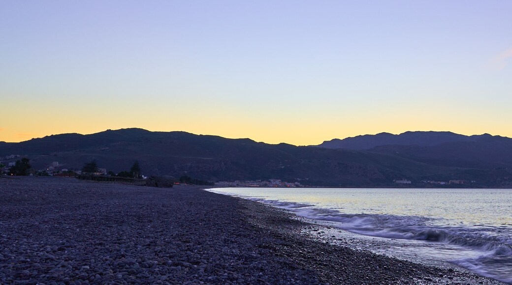The sunset on the pebble beach with hills on the background, Kolymbari, Crete, Greece.