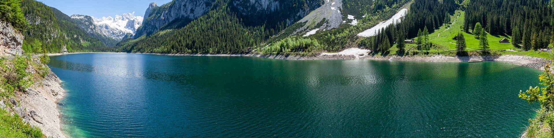Famous Lake Gosau and Gosaukamm with Mount Dachstein. Spring is here! The snow is melting and spring brings the luscious green back to nature. The sun is about to hide behind the high peaks.