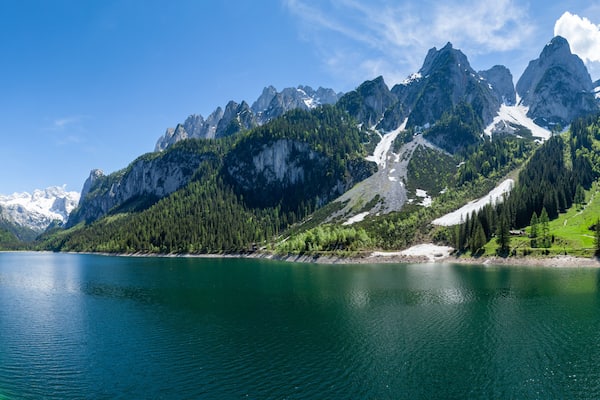 Famous Lake Gosau and Gosaukamm with Mount Dachstein. Spring is here! The snow is melting and spring brings the luscious green back to nature. The sun is about to hide behind the high peaks.