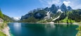 Famous Lake Gosau and Gosaukamm with Mount Dachstein. Spring is here! The snow is melting and spring brings the luscious green back to nature. The sun is about to hide behind the high peaks.