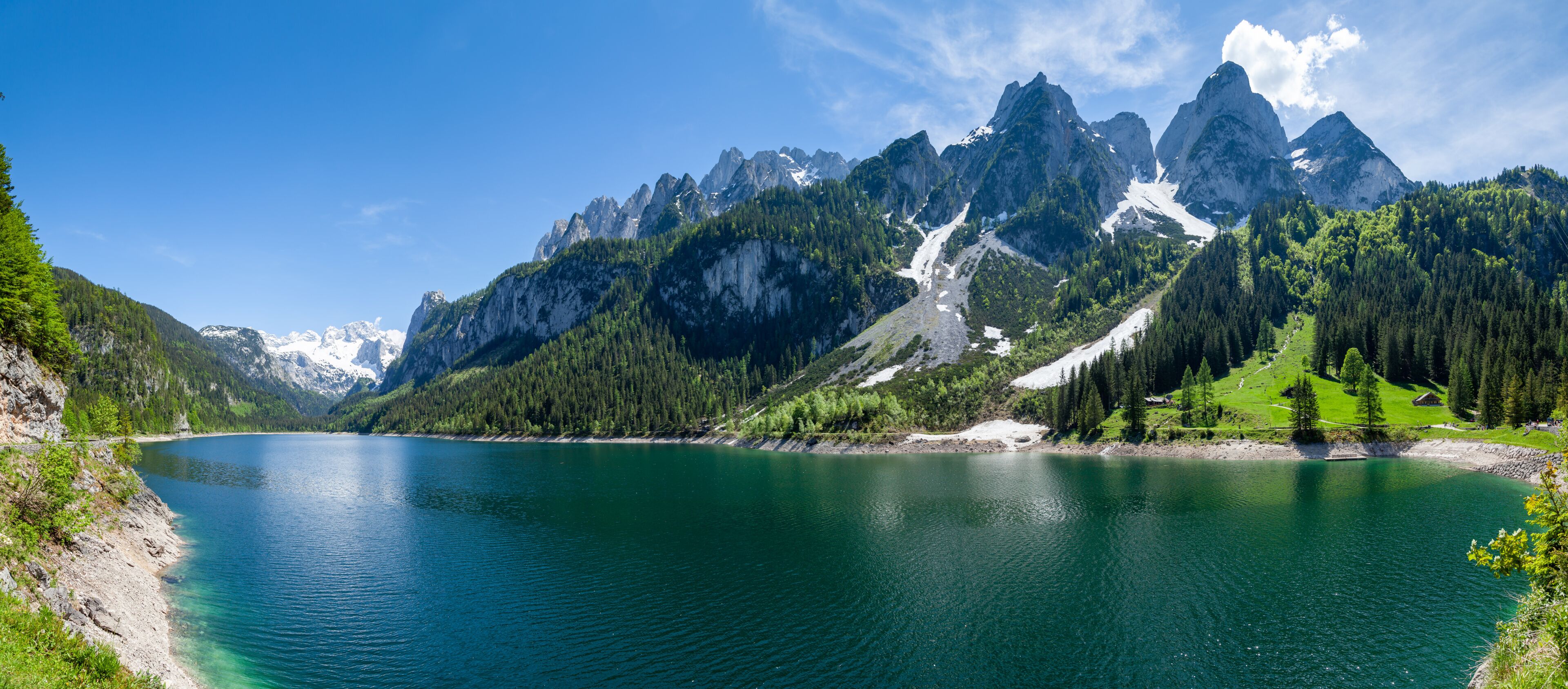 A mountain lake with clear turquoise water, surrounded by rugged mountains and dense forests.
