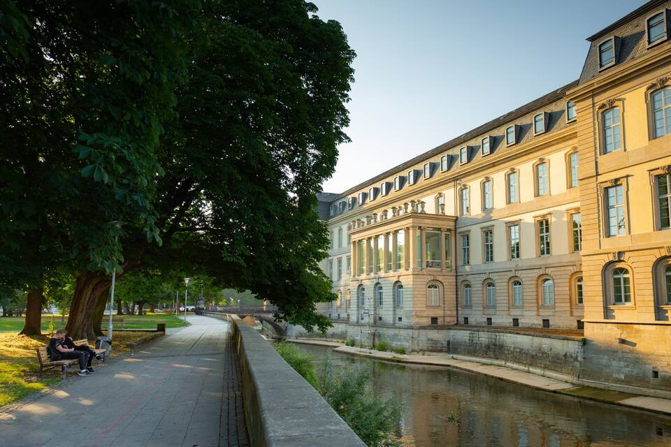 En historisk byggnad med klassisk arkitektur, en kanal och en allé.